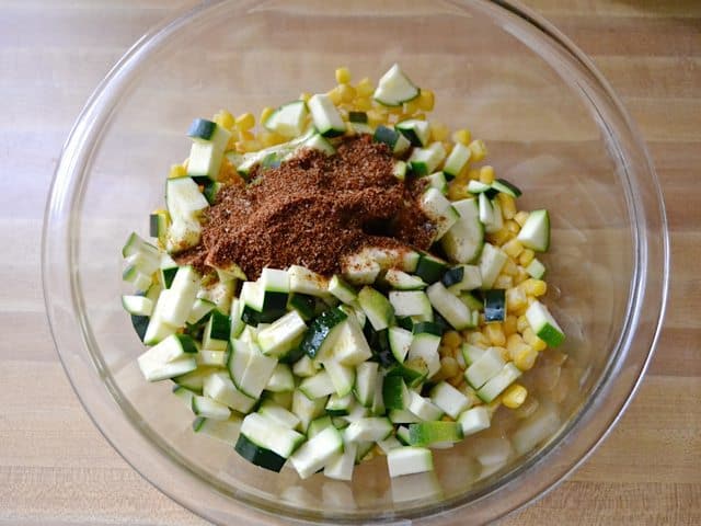 Chopped zucchini, corn and seasoning in mixing bowl 