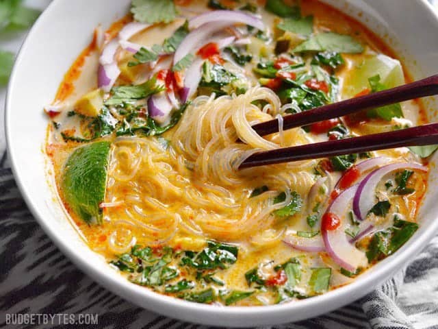 Close up of noodles wrapped around chopsticks in a bowl of Thai Curry Vegetable Soup.