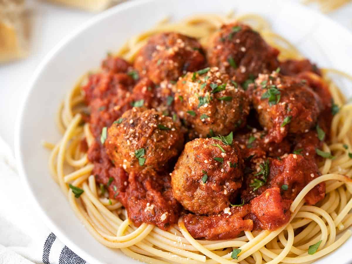 Side view of meatballs on a plate of spaghetti with red sauce