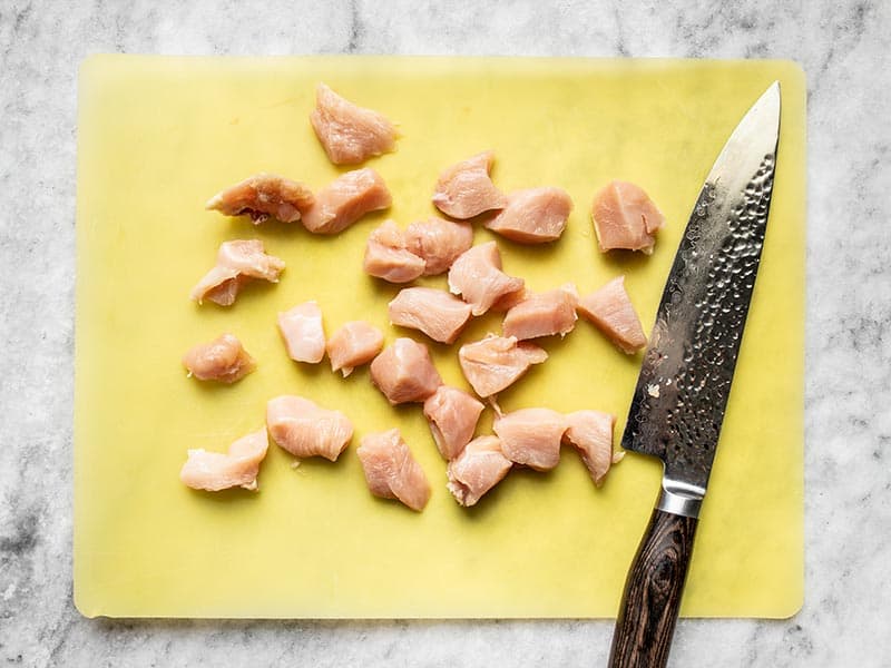 Cut chicken breast on a yellow cutting board. 