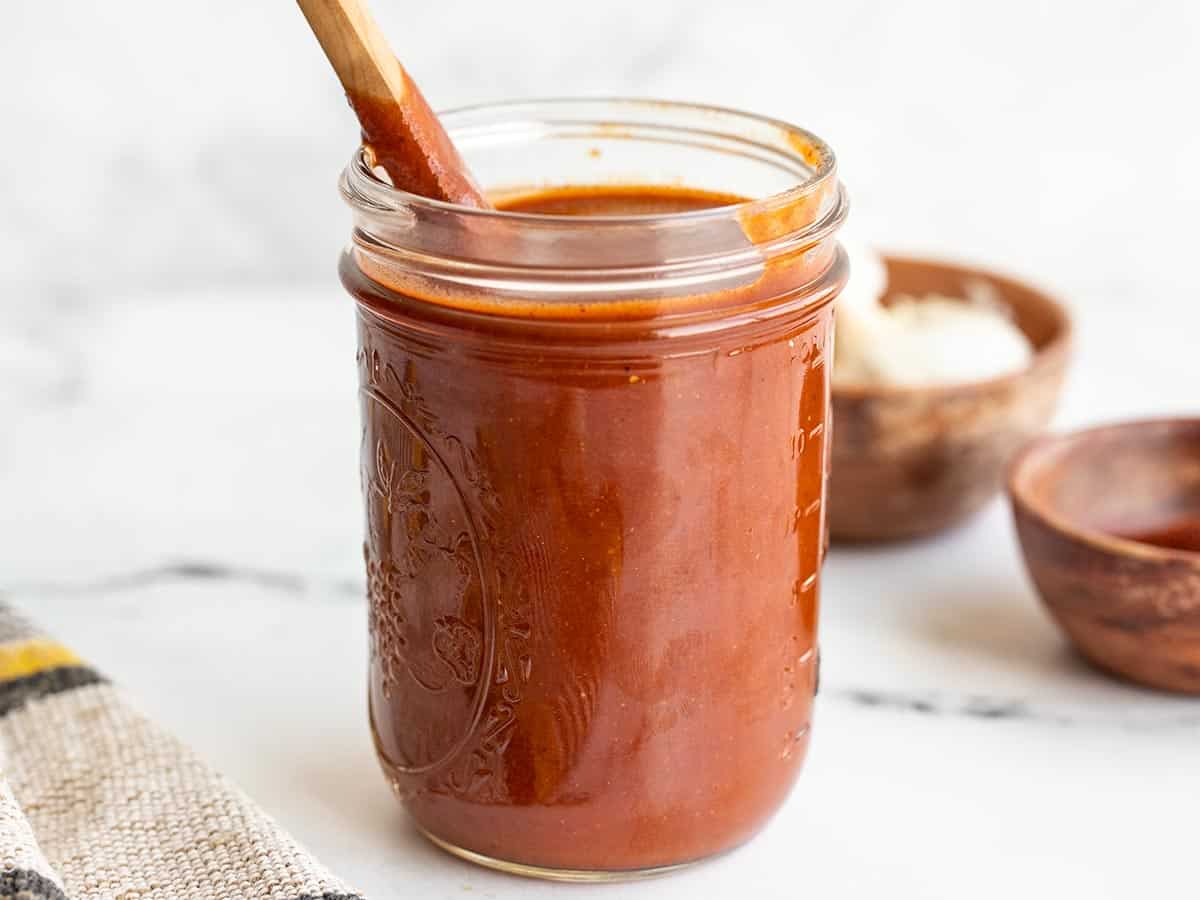 side view of a jar of enchilada sauce with a spoon.