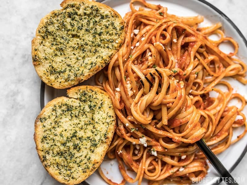 Two slices of freezer garlic bread on a plate with pasta