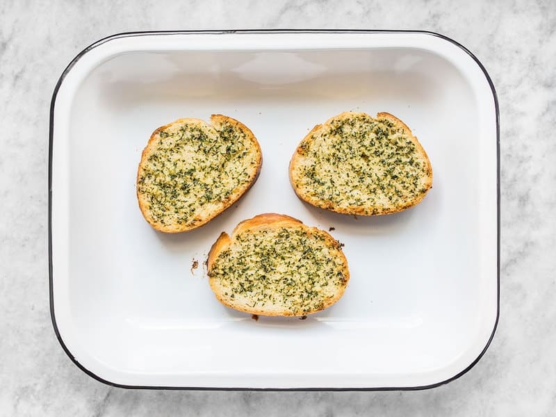 three garlic bread slices in a baking dish, baked