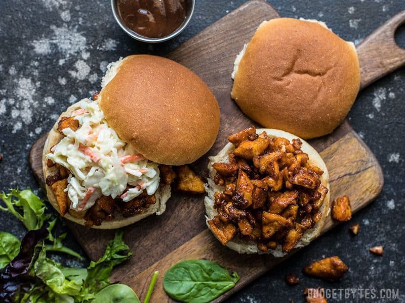 Two open BBQ Tofu Sliders with coleslaw on a wooden cutting board