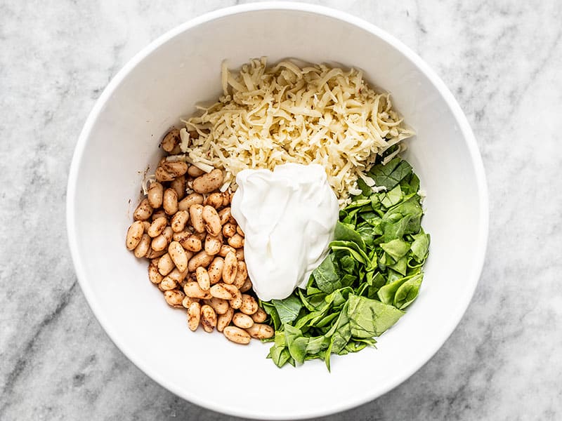 Beans, spinach, cheese, and sour cream in a bowl