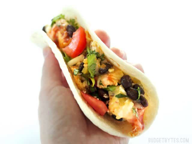 A hand holding a taco filled with Ultimate Southwest Scrambled Eggs 