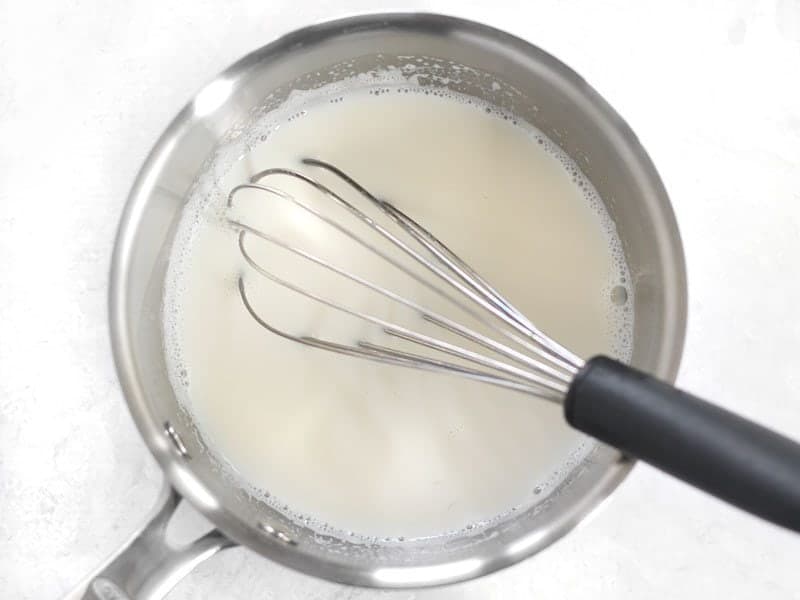 Hot milk in a sauce pan with a whisk