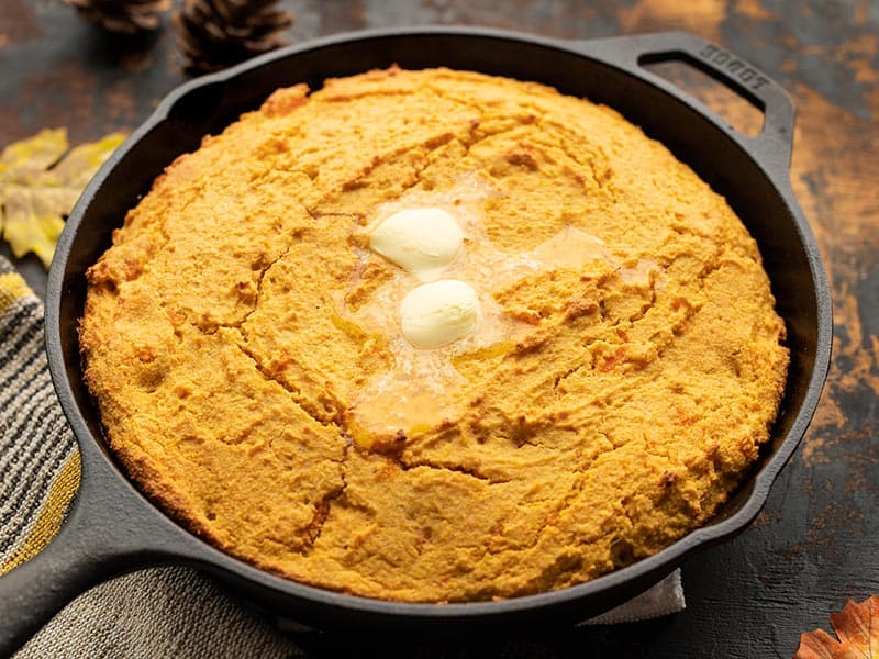 Front view of sweet potato cornbread in the skillet with butter melting on top