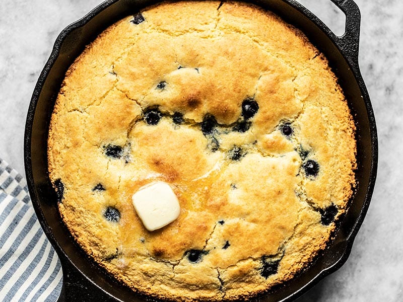 Close up of baked Lemon Blueberry Cornbread in the skillet with some butter melting on top.