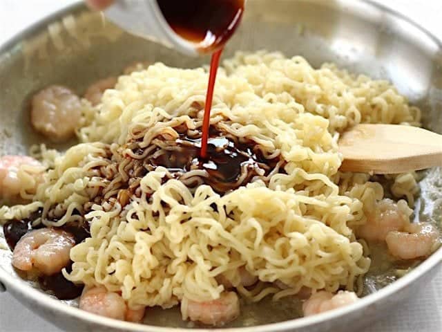 Ramen noodles added to the skillet and the dragon sauce being poured over top